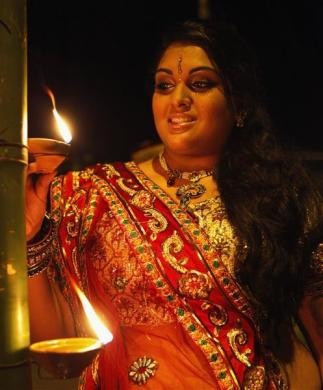 A woman places a diya, or earthen oil lamp, on a bamboo pole during Diwali celebrations in Felicity, central Trinidad. Diwali Celebrations
