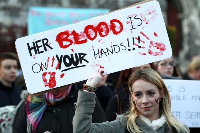 A woman holds a poster during a vigil in Dublin in memory of Savita Halappanavar and in support of changes to abortion law. The 31 year old's family claimed that she died after being repeatedly refused a termination during miscarriage