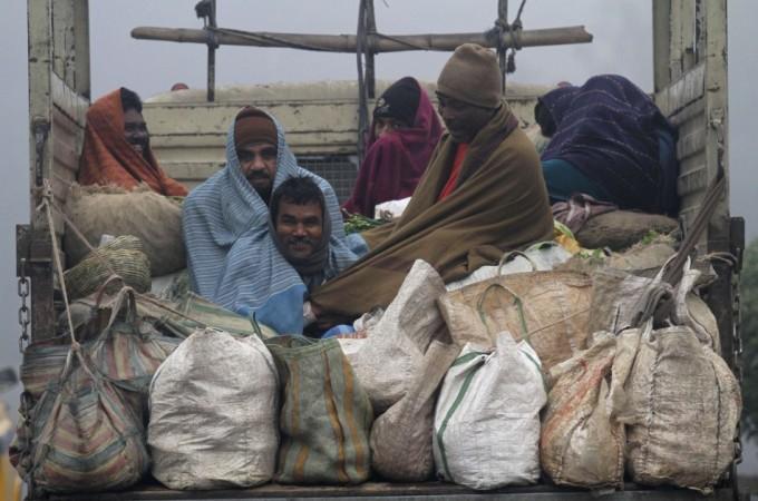 Vendors covered in blankets sit in the back of a supply truck after buying vegetables from a market on a cold winter morning in Kolkata Cold wave in north India