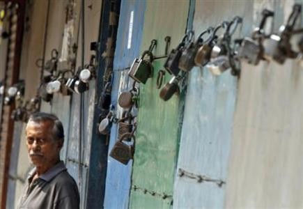 A man stands in front of closed shops during a nationwide strike in Kolkata September 20, 2012