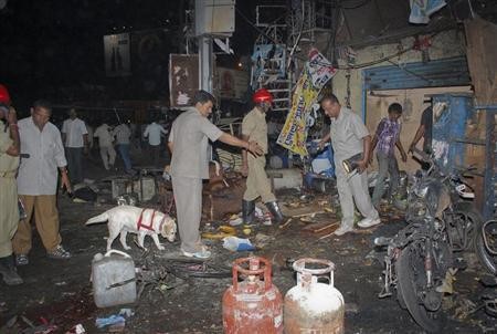 Investigating officers use a sniffer dog as they inspect the site of an explosion at Dilsukh Nagar, in Hyderabad February 21, 2013.