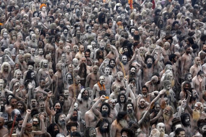 Naga Sadhus or Hindu holy men raise their arms while shouting religious hymns on the banks of the river Ganges after taking the holy dip during the third 'Shahi Snan' (grand bath) at the ongoing Kumbh Mela