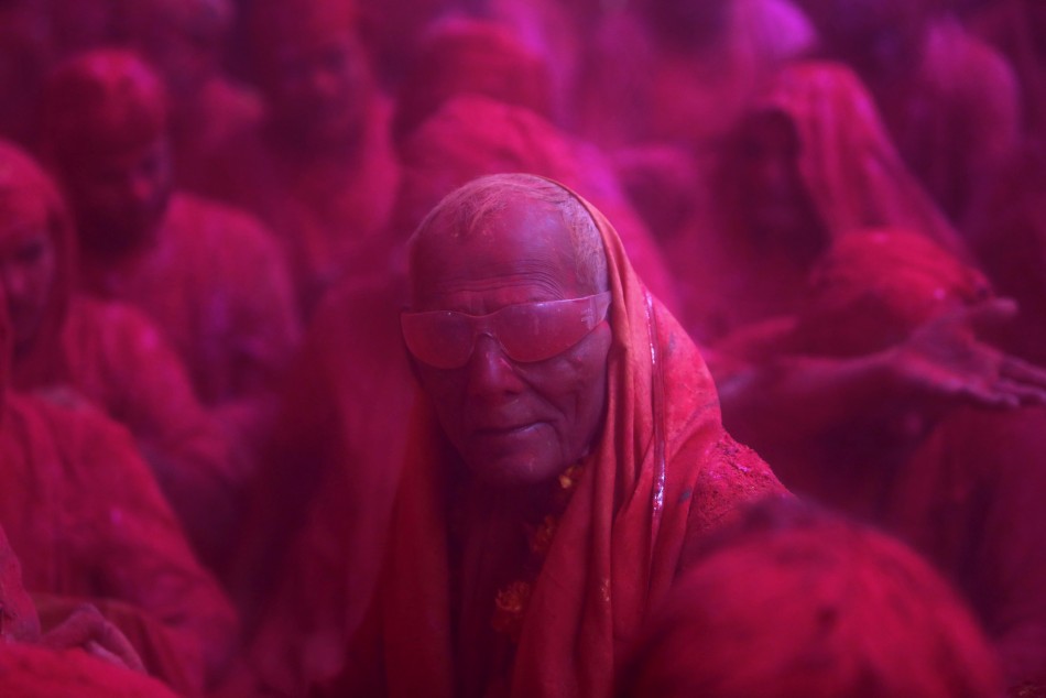 A Hindu devotee looks on in a cloud of coloured powder inside a temple during Lathmar Holi