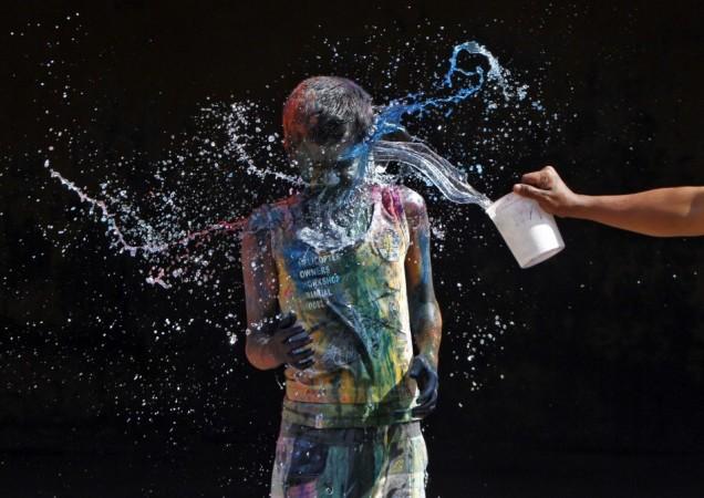 A boy smeared with colours reacts as another boy pours water on him during Holi celebrations in the southern Indian city of Chennai Holi 2013