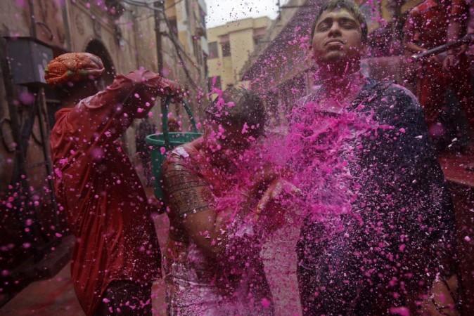 People splash coloured water on a woman as she walks in a lane during Holi celebrations in Vrindavan Holi 2013