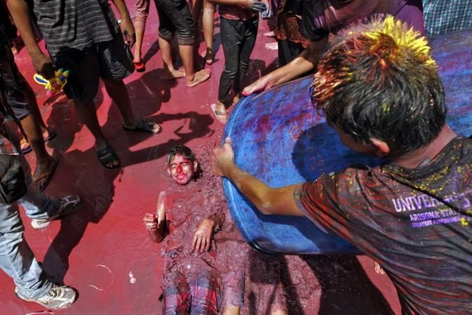 A boy lies in the ground as other boys pour coloured water on him during Holi celebrations in the southern Indian city of Chennai Holi 2013