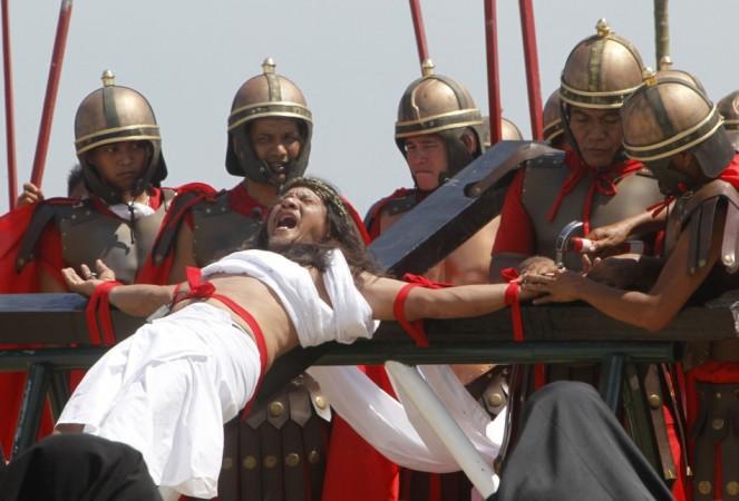 Enaje, who is portraying Jesus Christ, is raised on a wooden cross by a group of men playing Roman soldiers during a Good Friday crucifixion re-enactment in San Pedro Cutud Good Friday