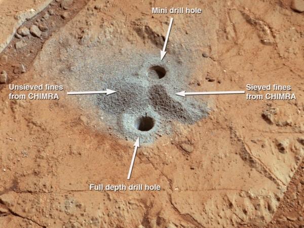 This image shows the first holes into rock drilled by NASA's Mars rover Curiosity, with drill tailings around the holes plus piles of powdered rock collected from the deeper hole and later discarded after other portions of the sample had been deliver