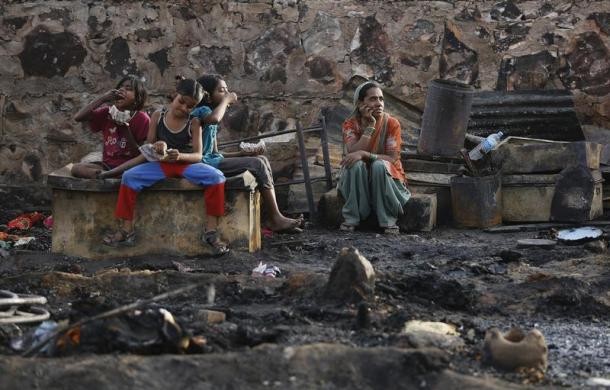 A family sits amid the burnt debris of their hut.