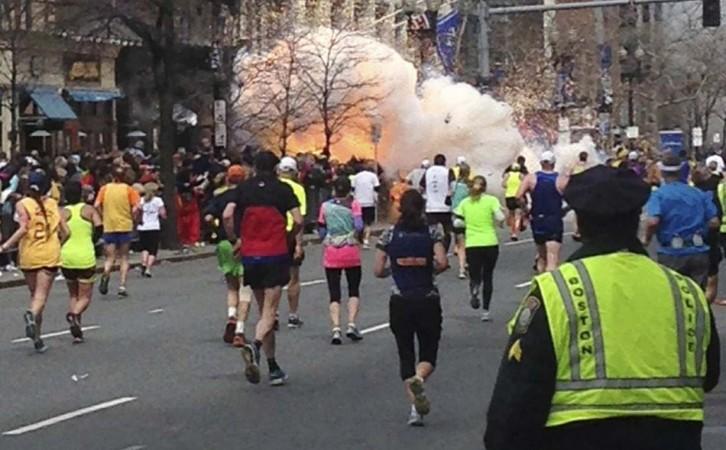 Runners continue to run towards the finish line as an explosion erupts at the finish line of the Boston Marathon Boston Marathon