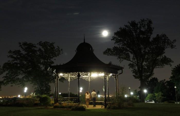 People walk through a gazebo as a full moon also referred to as a Supermoon 2013