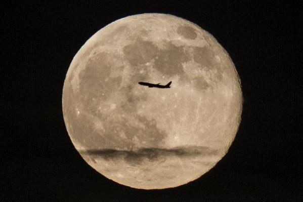 A silhouetted airplane flies past a 'supe rmoon' over New York. (Reuters) Supermoon