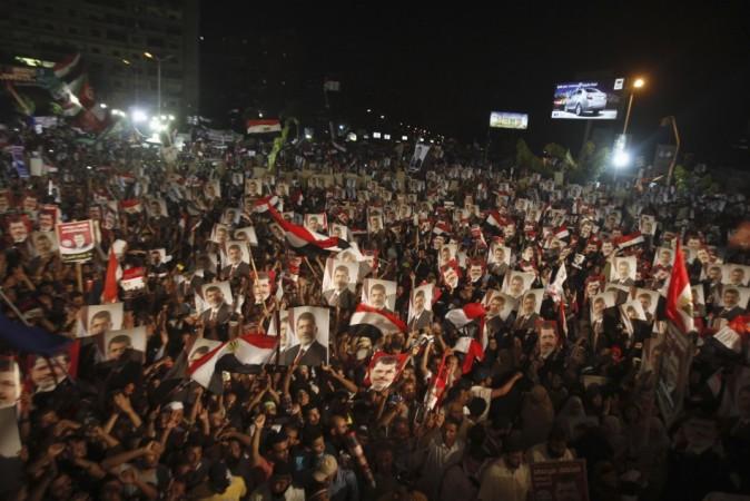 Supporters of Egypt's President Mohamed Mursi, holding his picture, react after the Egyptian army's statement was read out on state TV, at the Raba El-Adwyia mosque square in Cairo Egypt