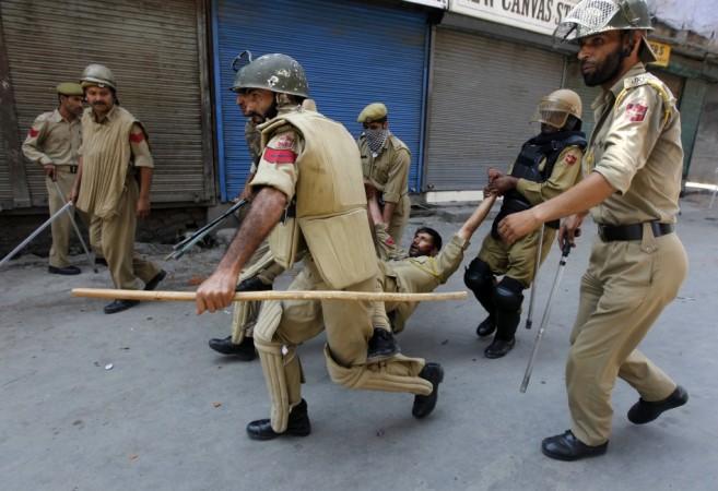 Indian policemen carry their injured colleague after he was wounded during a protest in Srinagar July 18, 2013.
