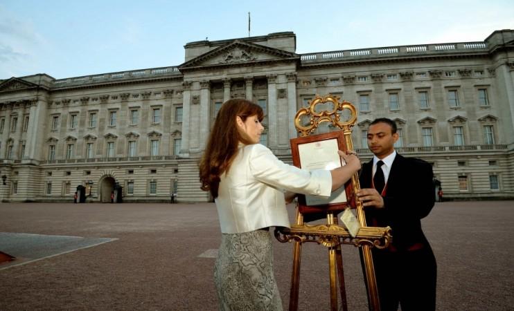 The press Secretary to Britain's Queen Elizabeth, Ailsa Anderson, and footman Badar Azim, place a notice formally announcing the birth of a son to Prince William and Catherine, Duchess of Cambridge, in the forecourt of Buckingham Palace, in central London Royal Baby