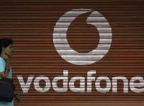 A woman walks past a large logo of Vodafone displayed on a shop in Mumbai May 20, 2010.