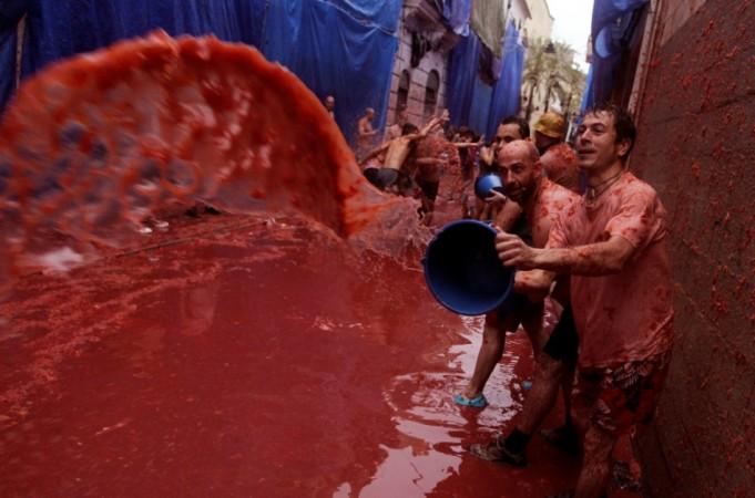 A reveller pours tomato pulp over others after the annual La Tomatina Festival 2013
