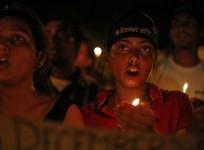 Demonstrators shout slogans as they hold candles during a candle light vigil