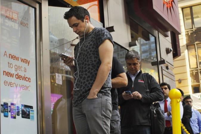 Customers wait in line to purchase the Apple iPhone 5S at an AT iPhone 5S