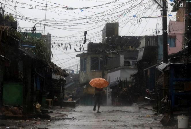 A man tries to cover himself with an umbrella during heavy rain brought by Cyclone Phailin as he moves towards a safer place at the village Donkuru in Srikakulam district in Andhra Pradesh Cyclone Phailin