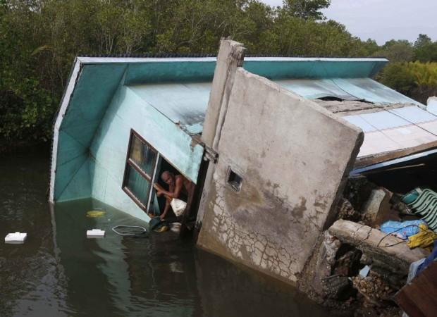 A resident looks out from the window of his family's house, that fell into a river after an earthquake, in Buenavista, Bohol a day after an earthquake hit central Philippines October 16, 2013. The death toll from a Philippine earthquake rose to 107 on Wed