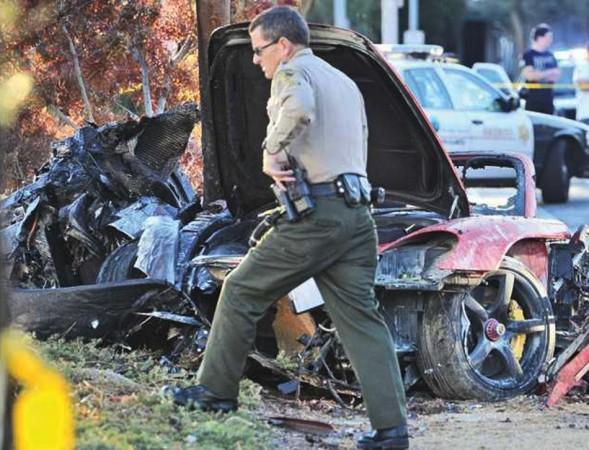 A police officer walks past the car where actor Paul Walker was killed along with another unidentified man during a car crash in Valencia Paul Walker