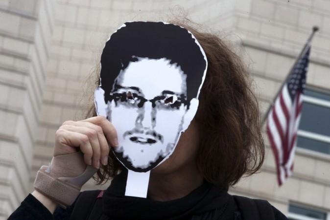 A woman holds a portrait of former US spy agency contractor Edward Snowden in front of her face as she stands in front of the US embassy during a protest in Berlin.