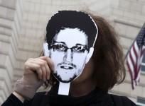 A woman holds a portrait of former US spy agency contractor Edward Snowden in front of her face as she stands in front of the US embassy during a protest in Berlin.