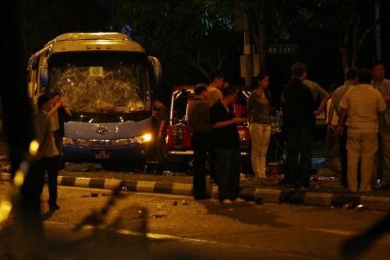 Officials stand around a bus with a smashed windshield following a riot in Singapore's Little India district, December 9, 2013.