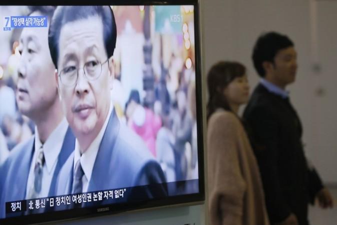 A couple walks past a television showing a report on Chang Song-thaek, North Korean leaders' uncle, at a railway station in Seoul (Reuters)