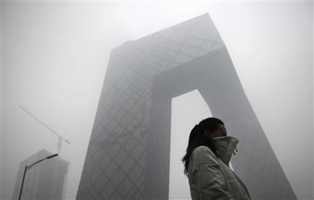 A woman walks past the new China Central Television (CCTV) building amid heavy fog in Beijing, December 5, 2011.