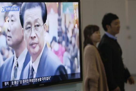 A couple walks past a television showing a report on Jang Song Thaek, North Korean leaders' uncle, at a railway station in Seoul December 3, 2013.