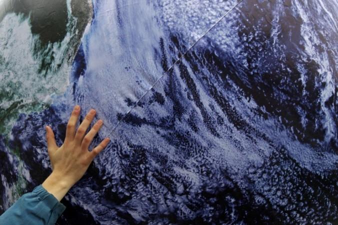 An environmental activist places his hand on a giant globe in a rally demanding more action to battle climate change during the 19th conference of the United Nations Framework Convention on Climate Change (COP19) in Warsaw November 16, 2013.