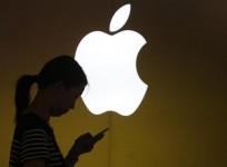 a-woman-looks-at-the-screen-of-her-mobile-phone-in-front-of-an-apple-logo-outside-its-store-in-downtown-shanghai-september-10-2013