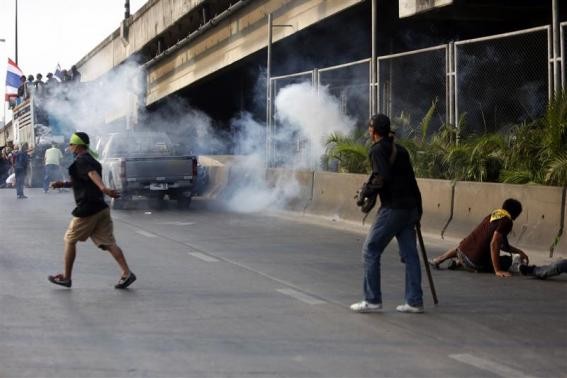 Anti-government protesters run as an explosion takes place near their vehicle during a gunfight between supporters and opponents of Thailand's government