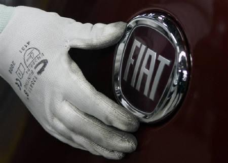 A worker adjusts the logo on a new Fiat Punto at a Fiat factory assembly line in the central Serbian town of Kragujevac