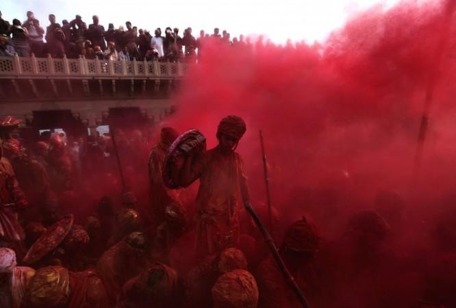 People throw coloured powder as they celebrate Lathmar Holi