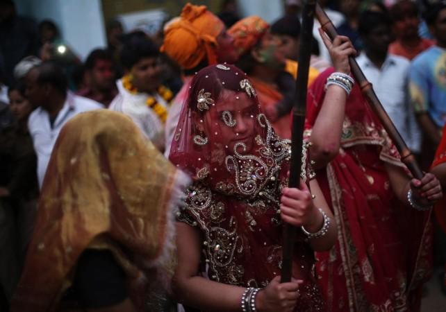 A veiled Hindu woman holds a bamboo stick as she celebrates Lathmar Holi