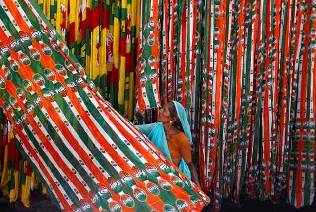 A worker pulls a roll of flags of India's ruling Congress party, kept for drying at a flag manufacturing factory, ahead of the 2014 general elections