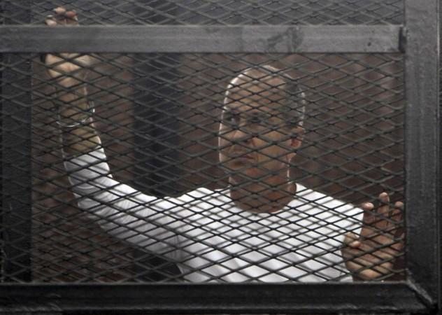Al Jazeera journalist Peter Greste of Australia stands in a metal cage during his trial in a court in Cairo March 24, 2014. Greste along with Fadel Fahmy and Baher Mohammed have been granted a retrial. Al Jazeera journalist Peter Greste of Australia stands in a metal cage during his trial in a court in Cairo