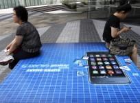 file-picture-shows-people-holding-their-mobile-phones-as-they-sit-on-an-advertisement-of-samsung-electronics-galaxy-s-smartphone-in-seoul