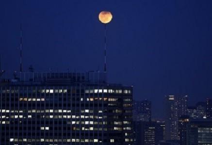 The partial lunar eclipse is seen atop an antenna installed on the roof of a high-rise building in Tokyo (Reuters)