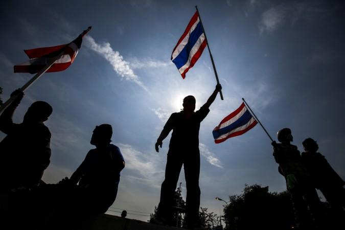Anti-government protesters wave Thai national flags after they toppled barricades near the Government House in Bangkok