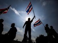 Anti-government protesters wave Thai national flags after they toppled barricades near the Government House in Bangkok