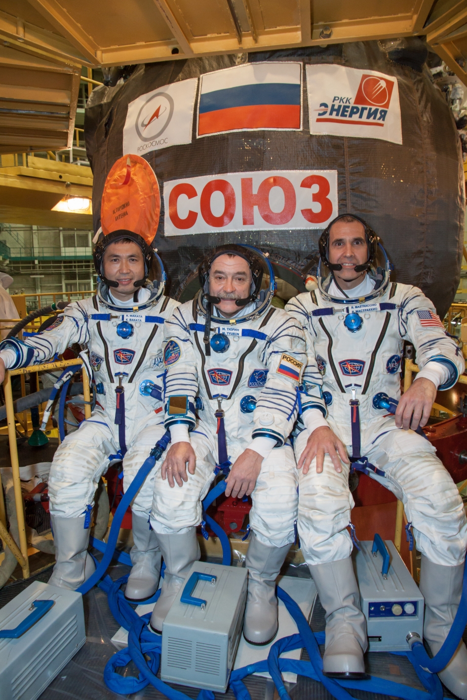 In the Integration Facility at the Baikonur Cosmodrome in Kazakhstan, Expedition 38/39 Flight Engineer Koichi Wakata of the Japan Aerospace Exploration Agency (left), Soyuz Commander Mikhail Tyurin (center) and Flight Engineer Rick Mastracchio of NASA (ri