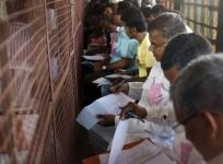 Voting agents from various political parties make notes as polling officials count votes at a counting centre in Allahabad