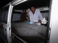 Mohammad Iqbal sits next to his wife Farzana's body, who was killed by family members, in an ambulance outside of a morgue in Lahore