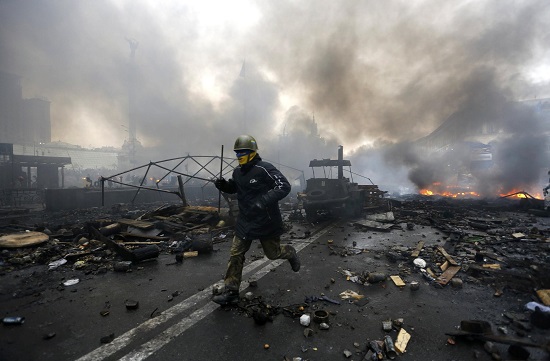 An anti-government protester runs trough the rubble after violence erupted in Ukraine protests