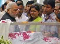 Modi looks at the casket of Munde, next to Munde's daughter, at BJP headquarters in New Delhi