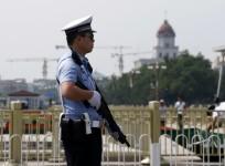 Policeman stands guard with a shotgun in front of Tiananmen Square in Beijing